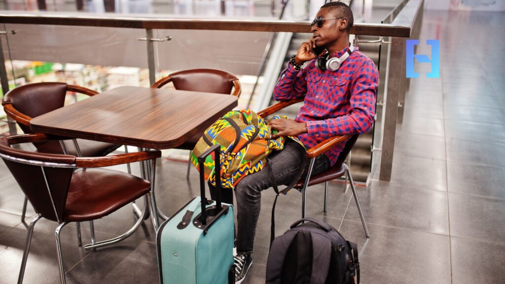 Homem esperando no aeroporto com malas depois de ter seus voos remarcados